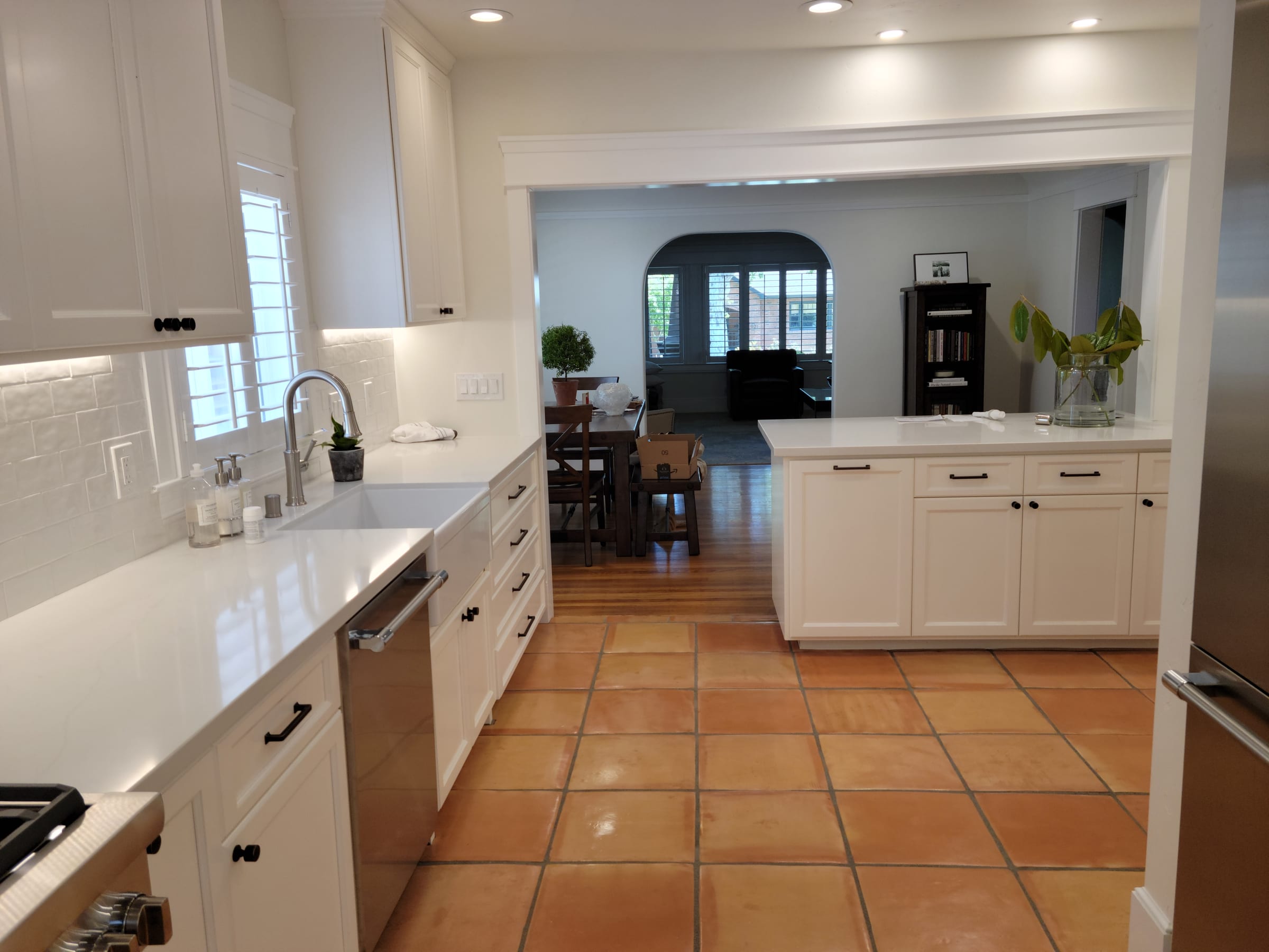 Kitchen island and terracotta tile floor, with a view through to the dining and living rooms