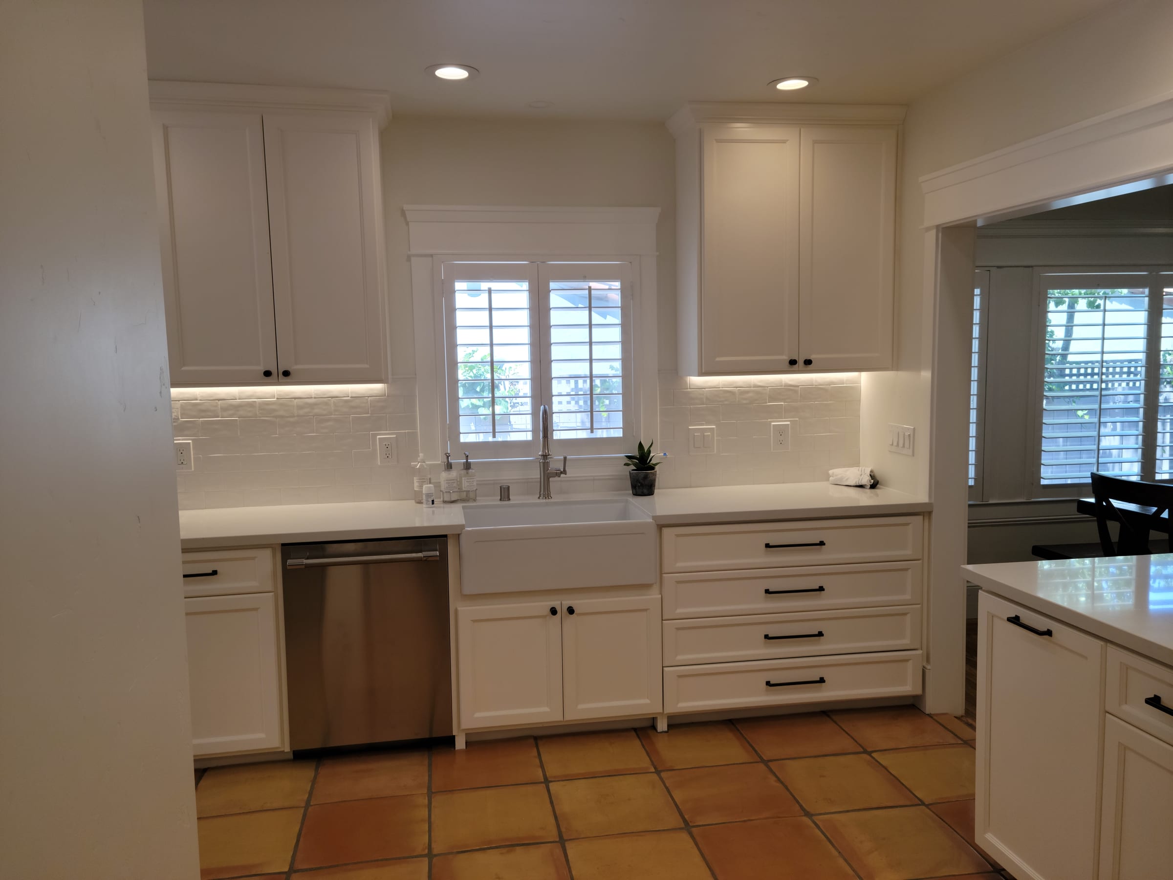 Farmhouse sink and white cabinets with black hardware, close view