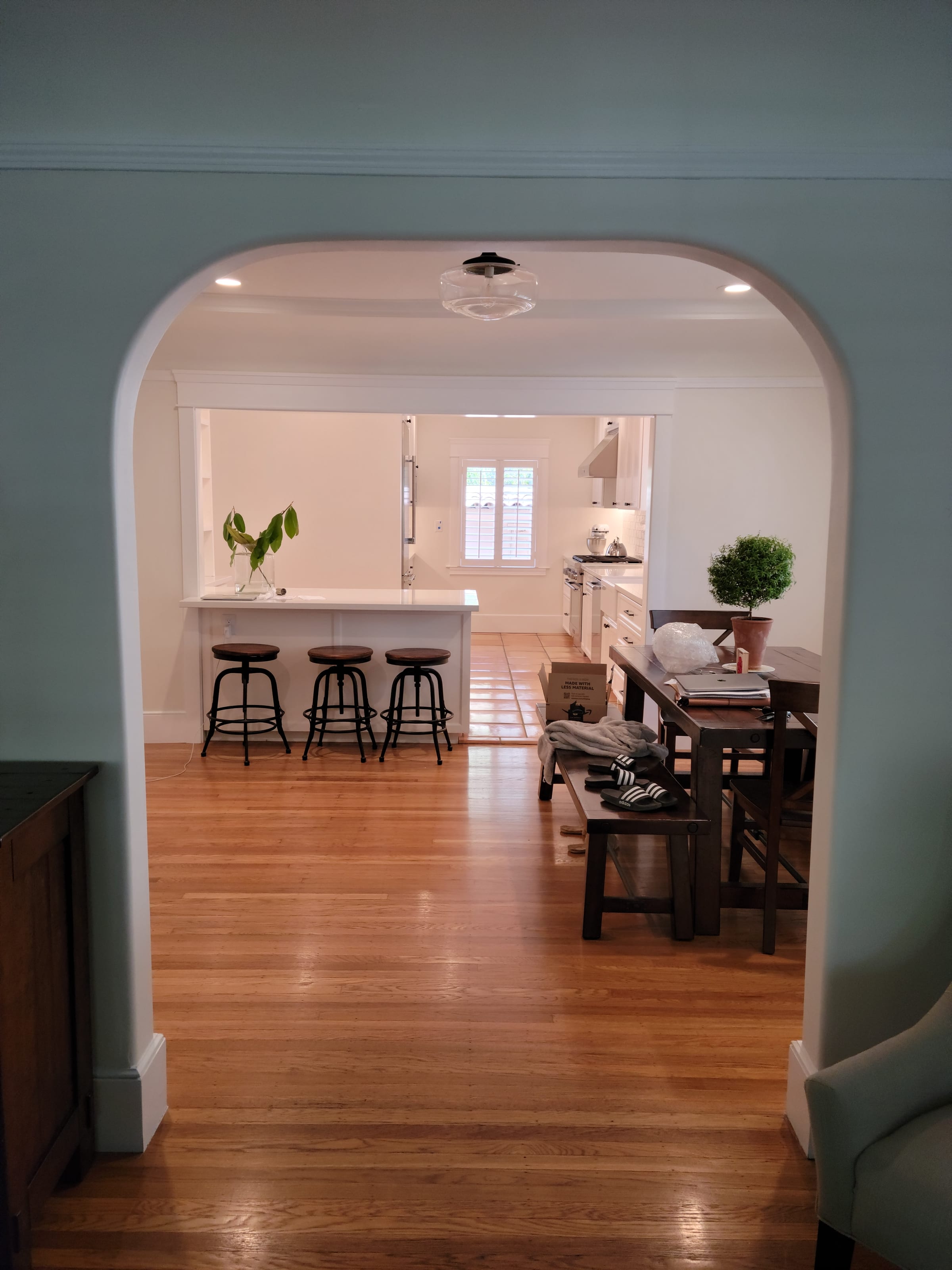 View into the kitchen through an arched doorway, with a kitchen island and bar stools