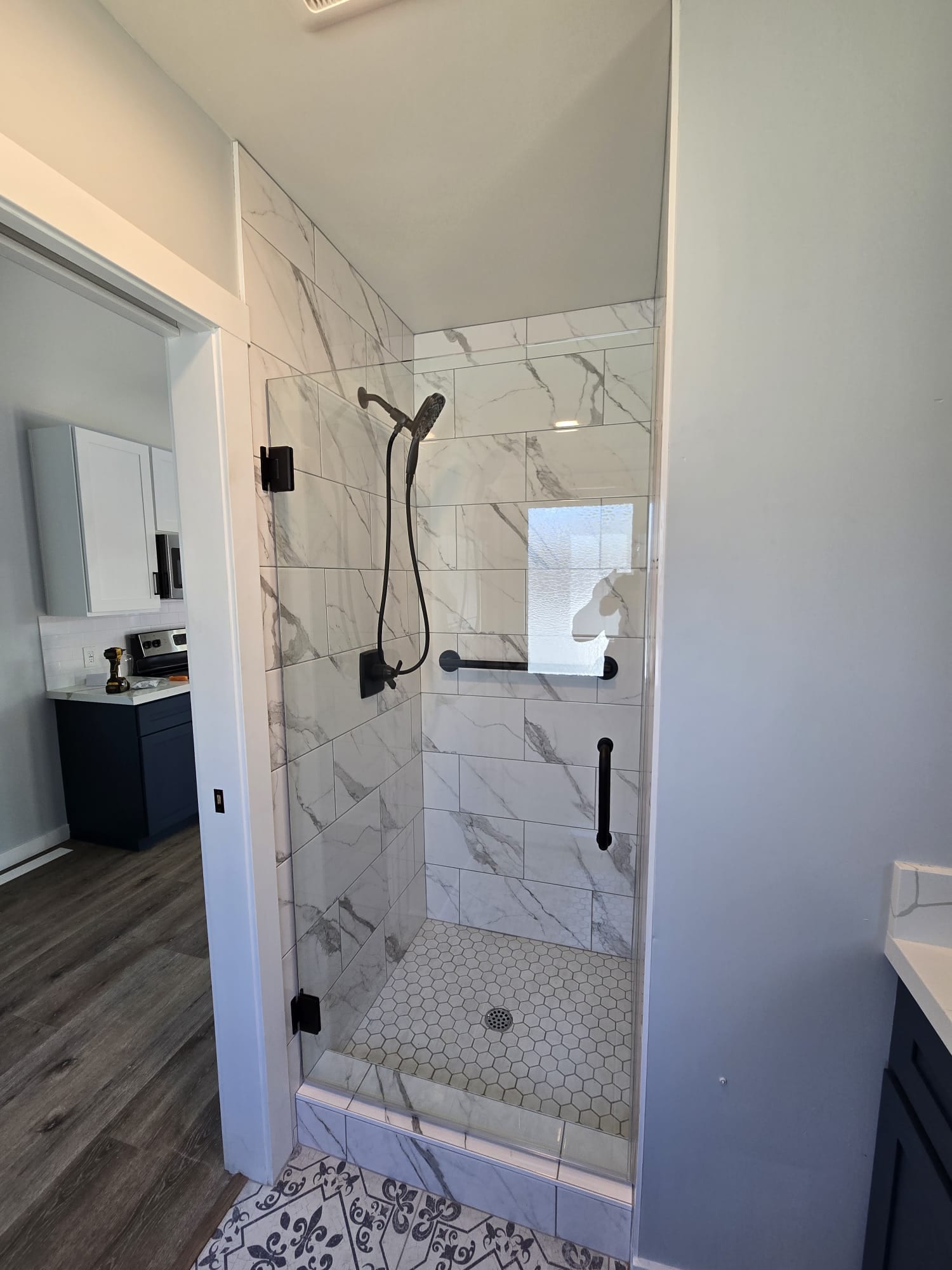47th St. ADU bathroom with marble-look tile shower and patterned floor tile