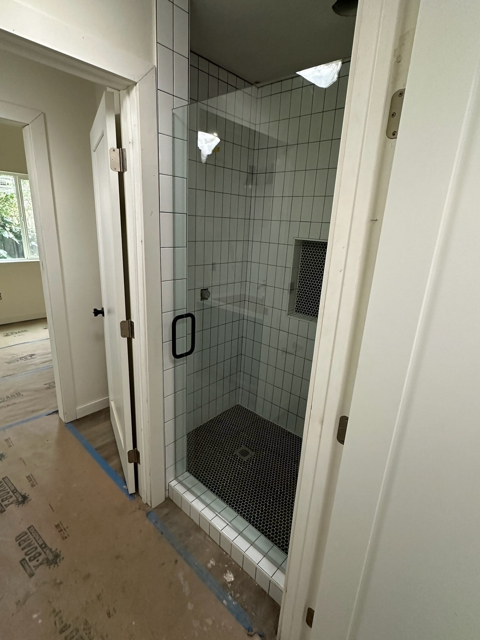 48th St. ADU bathroom with white subway tile shower and black penny-tile floor