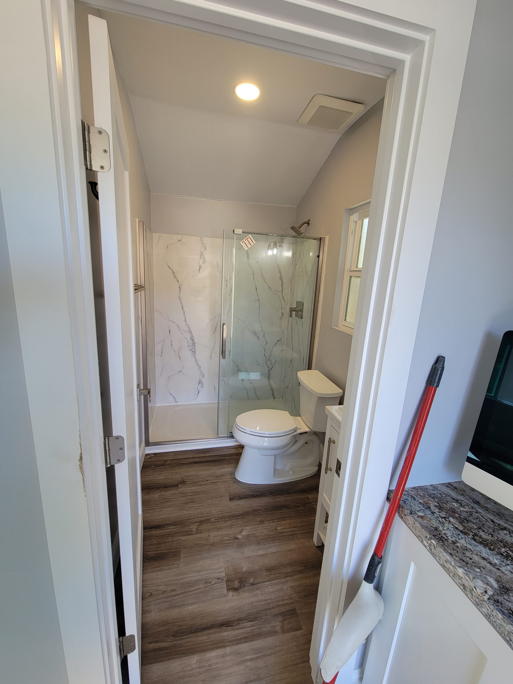 ADU bathroom with tiled glass shower, hallway view