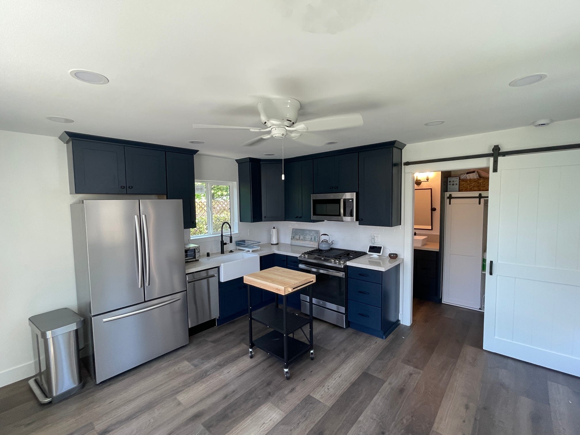 ADU kitchen with navy cabinets, stainless appliances and a sliding barn door
