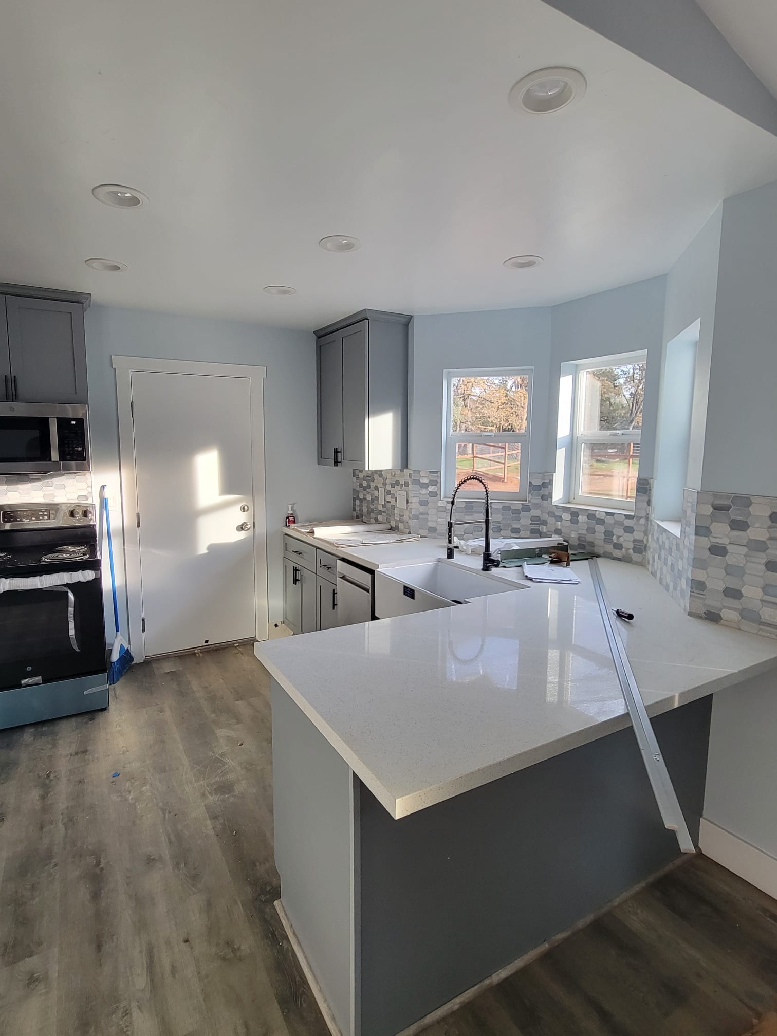 Gray kitchen cabinets with quartz counters and a hexagon mosaic tile backsplash