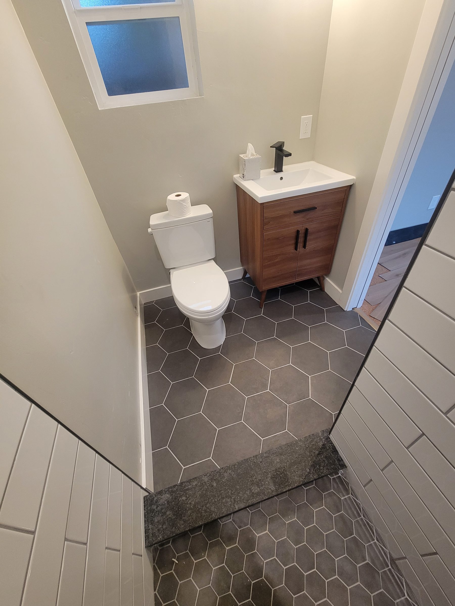 Modern ADU shower niche with hexagon tile and granite shelf