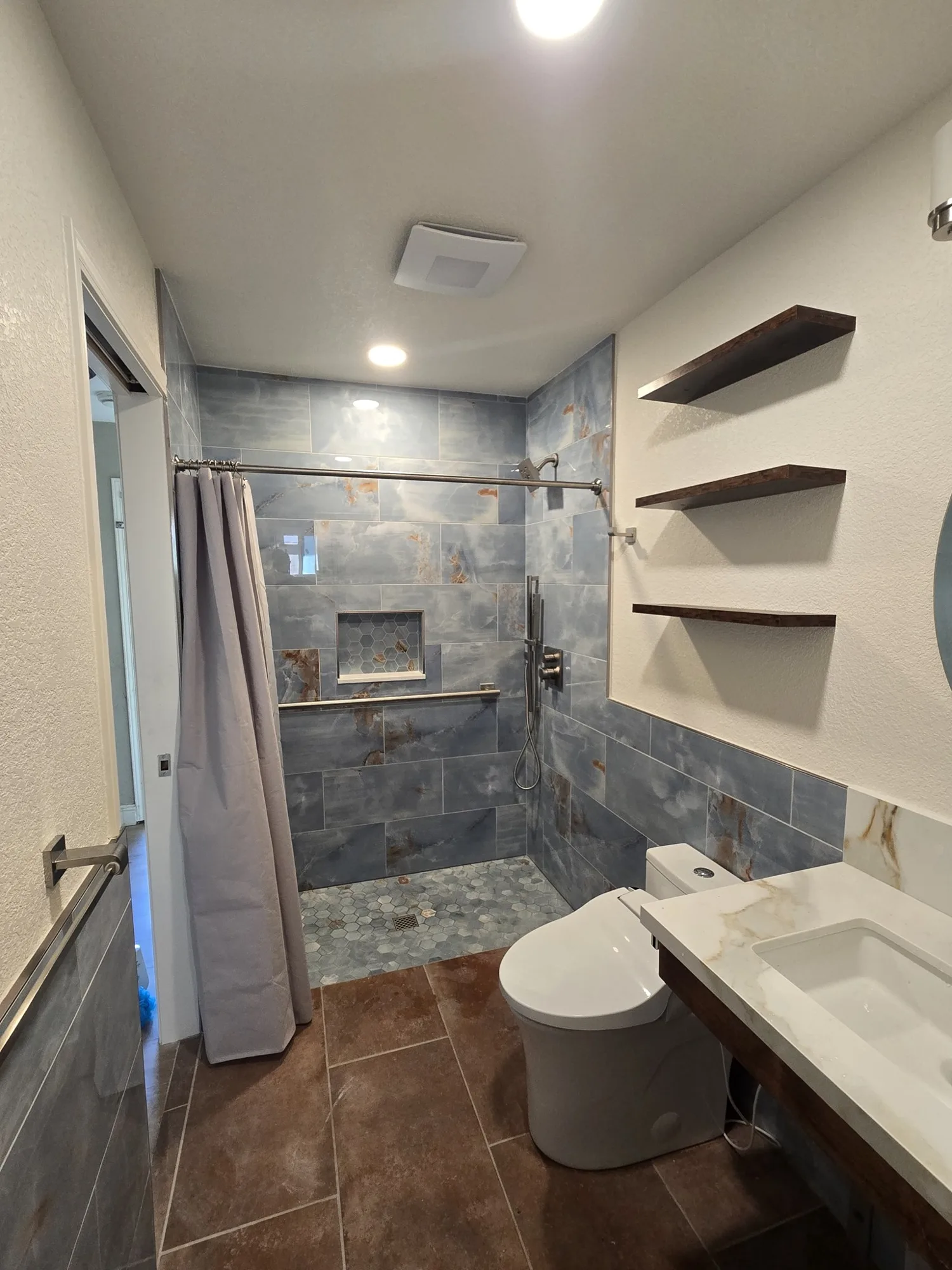 Wet room view from the shower toward the floating vanity and shelves