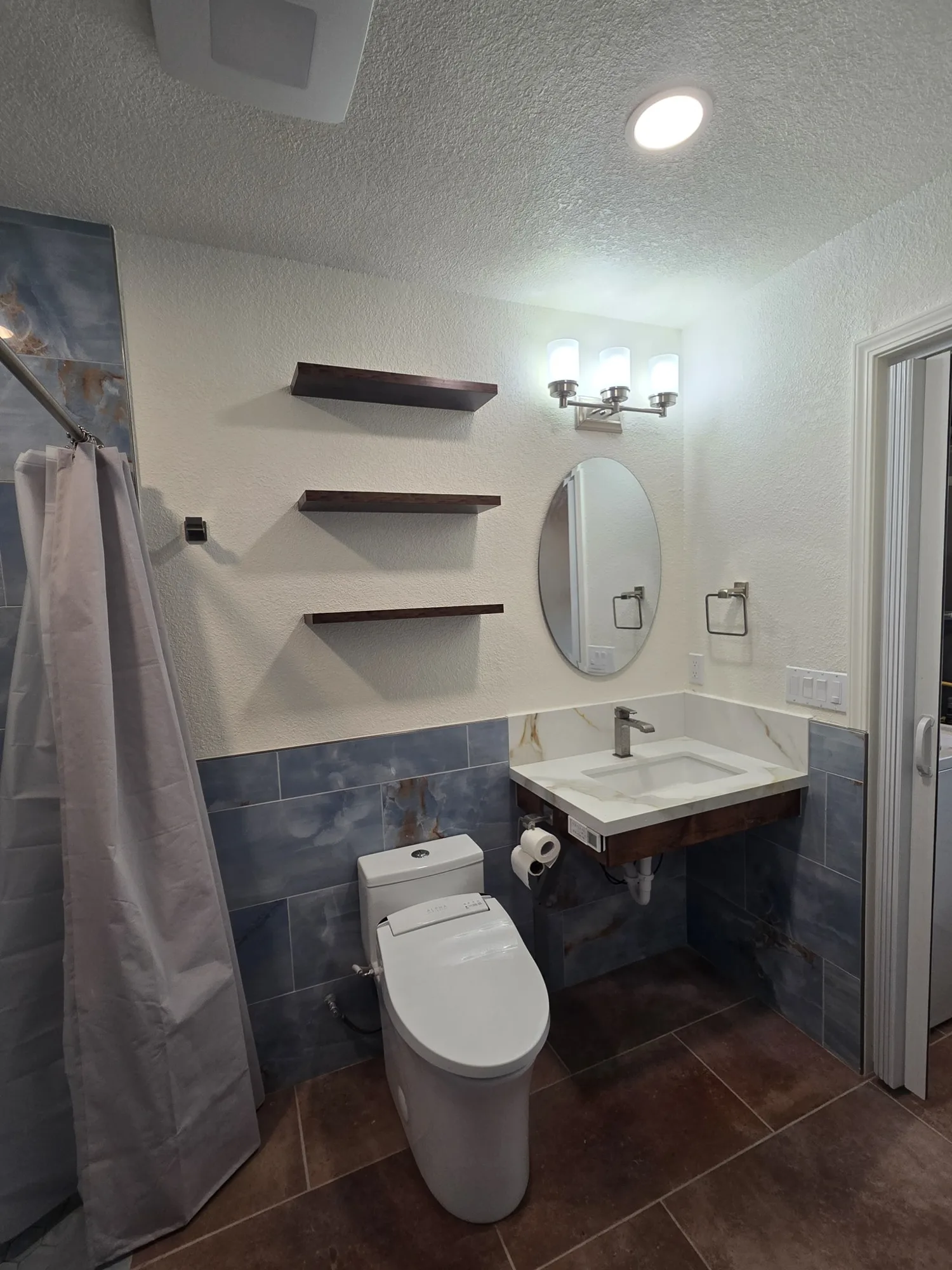 Dark wood floating shelves above the toilet and floating vanity