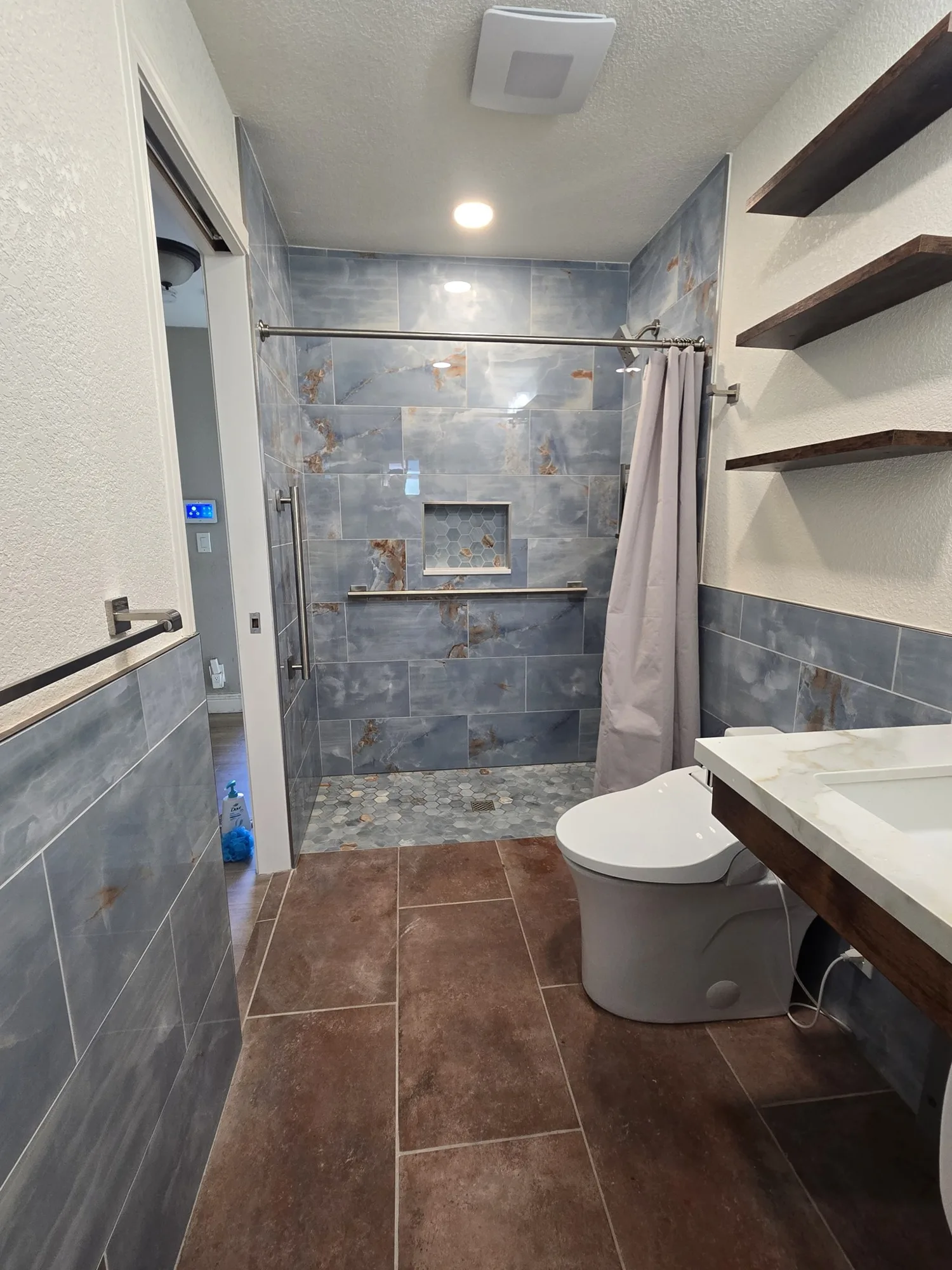 Full view of the accessible wet room with curbless shower, toilet and floating vanity