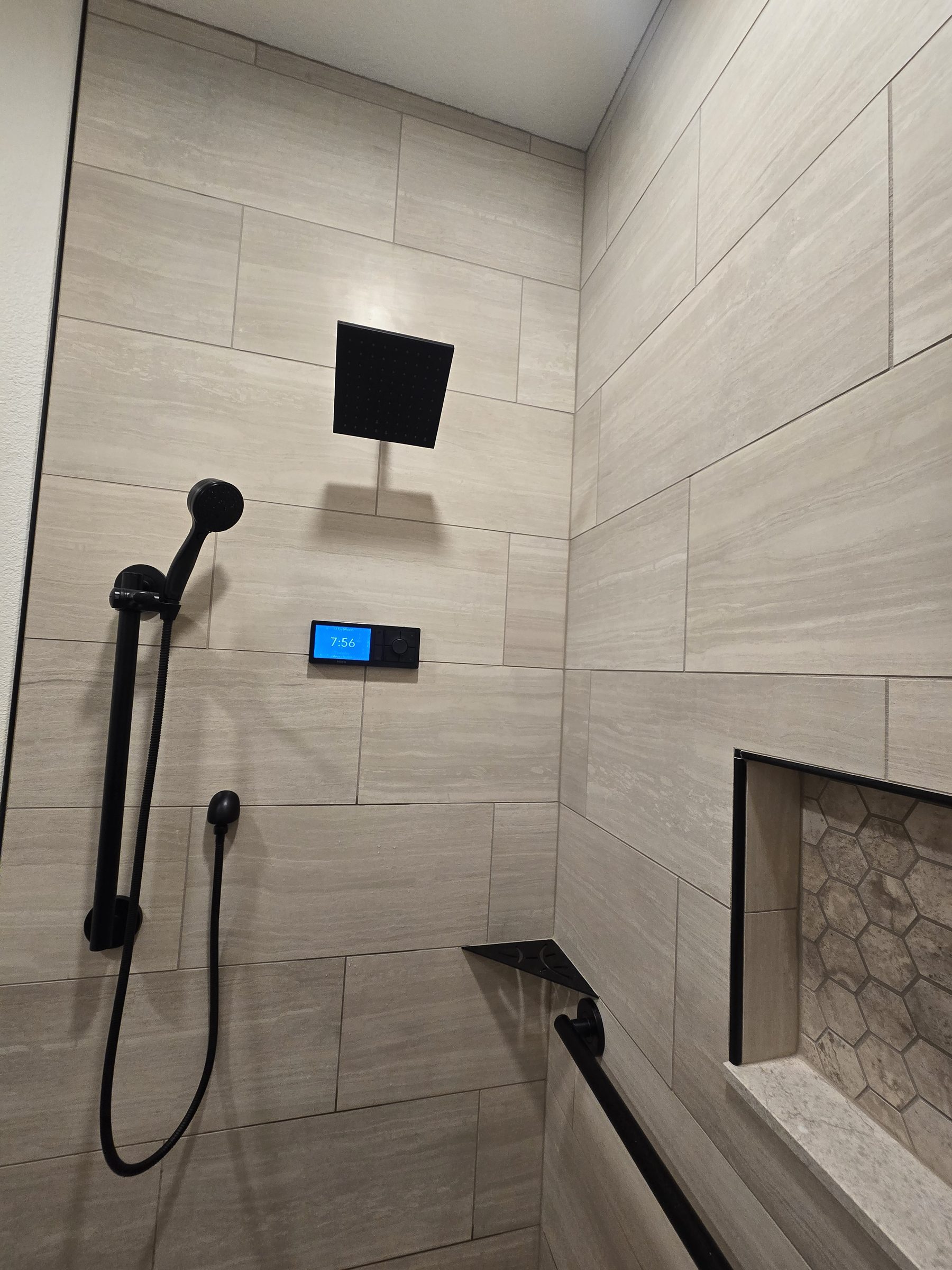 Curbless shower with hexagon tile floor and grab bars, corner view