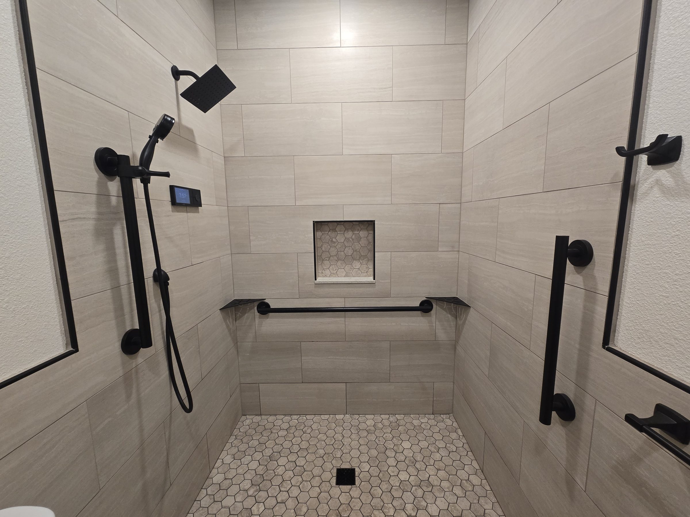 Curbless shower with handheld sprayer and grab bar