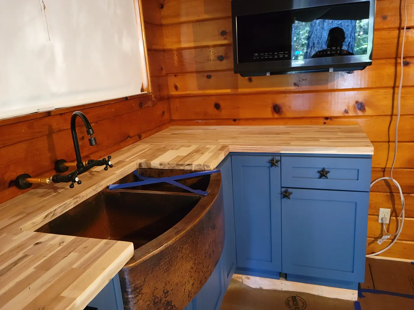 Close view of custom wood counters, sink, and blue cabinets