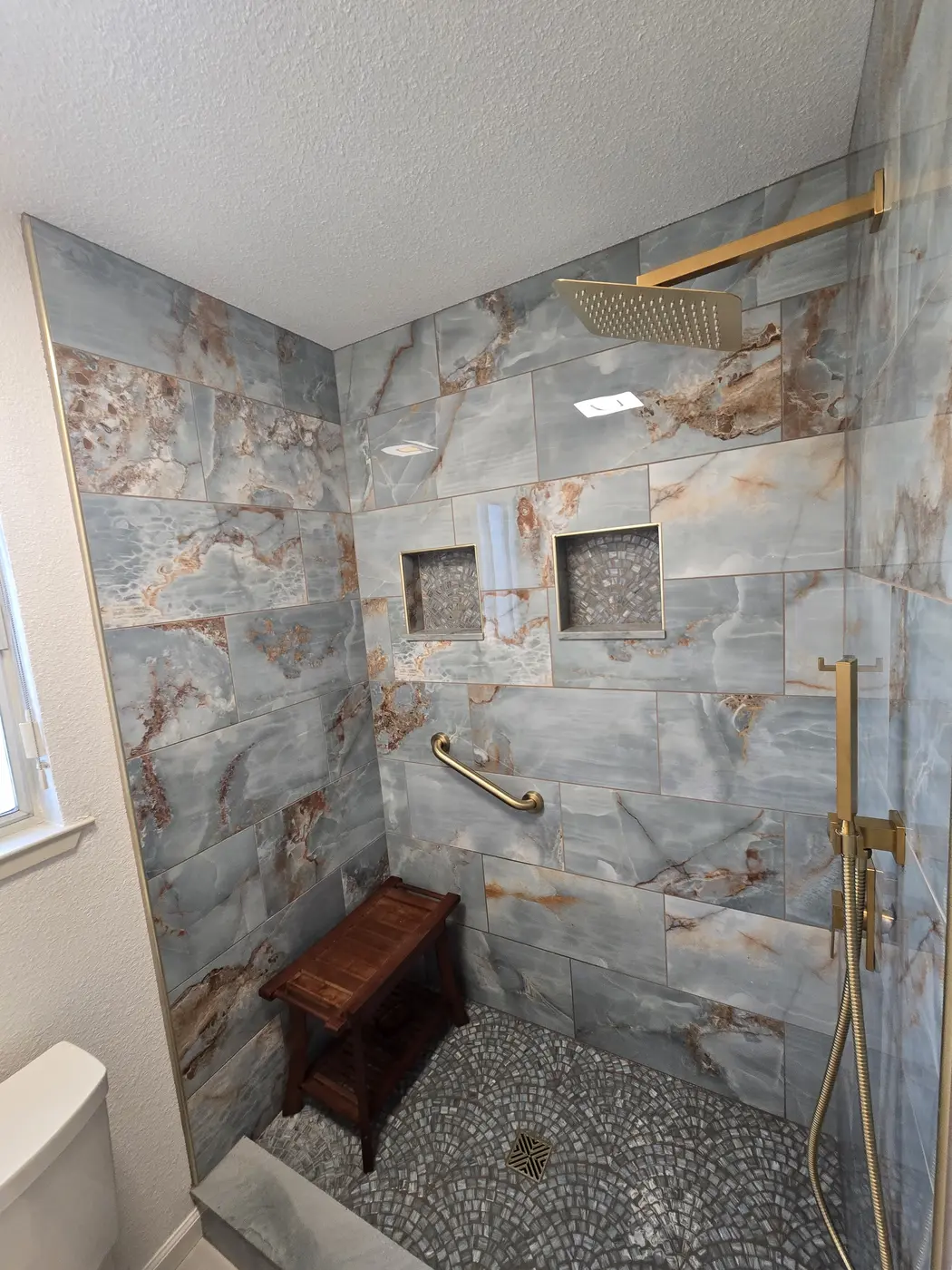 Close view of blue stone shower tile, niches, and pebble floor