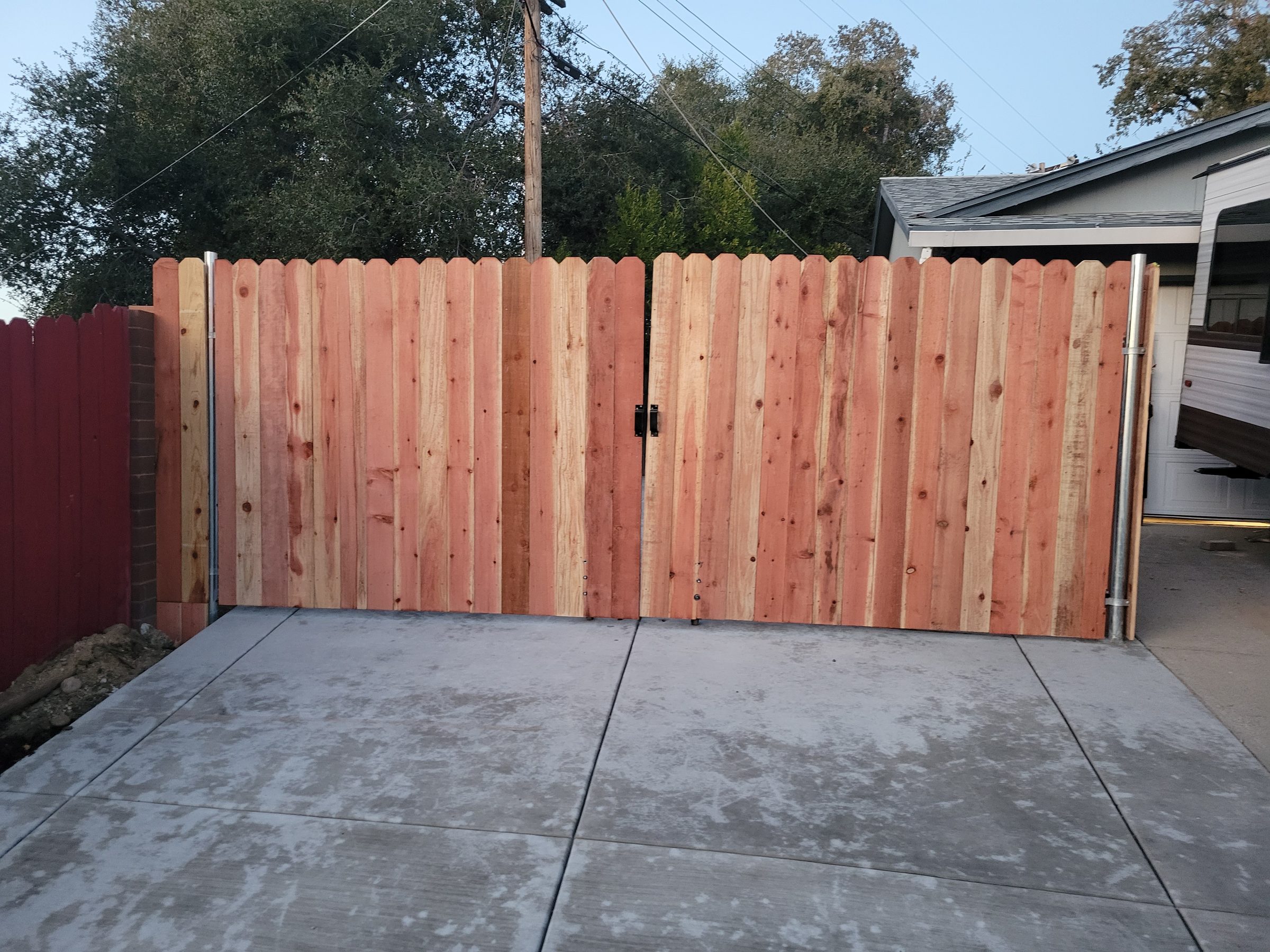 New concrete driveway pad with a wood double gate along the back