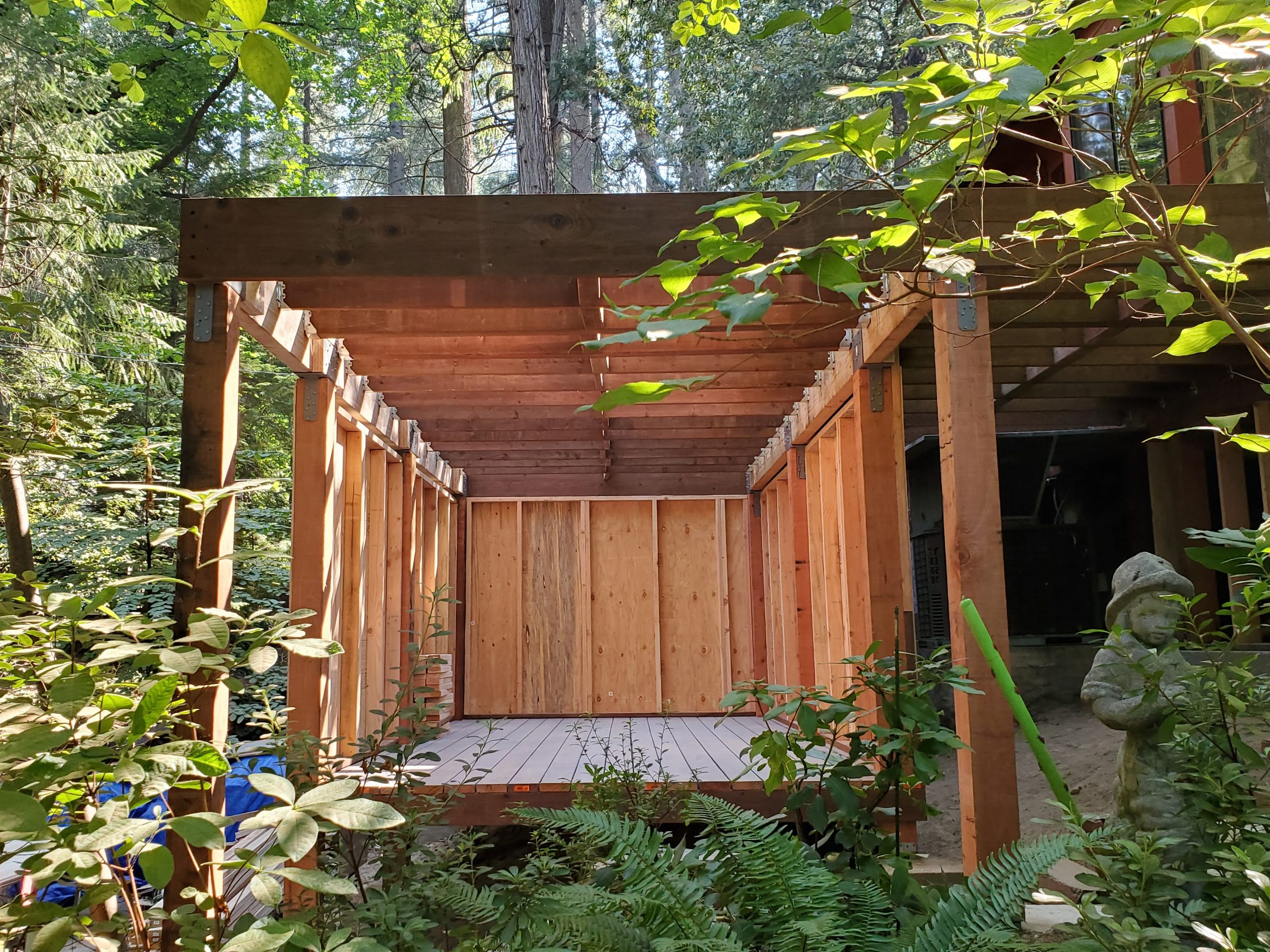 Wood-framed deck and storage structure tucked into a wooded backyard