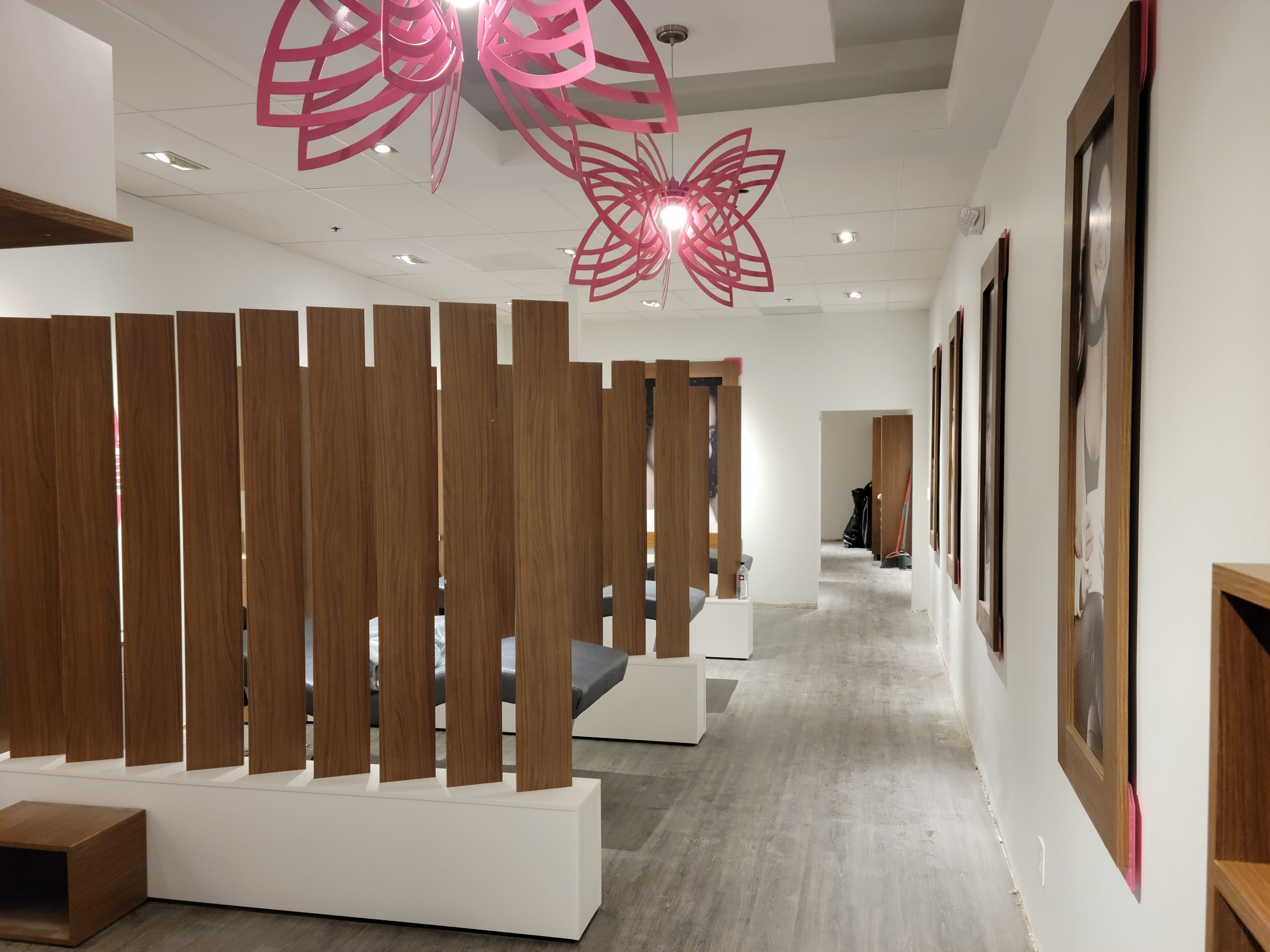 Wood-slat privacy dividers between treatment benches under sculptural pink pendant lighting