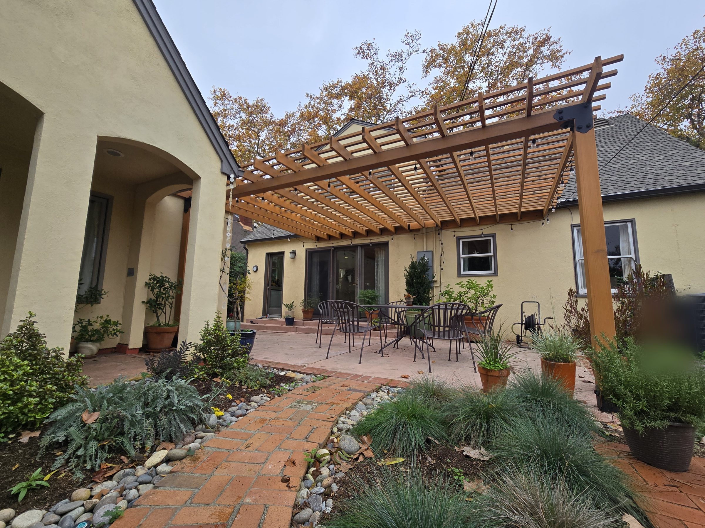 Finished dining pergola with string lights over patio seating