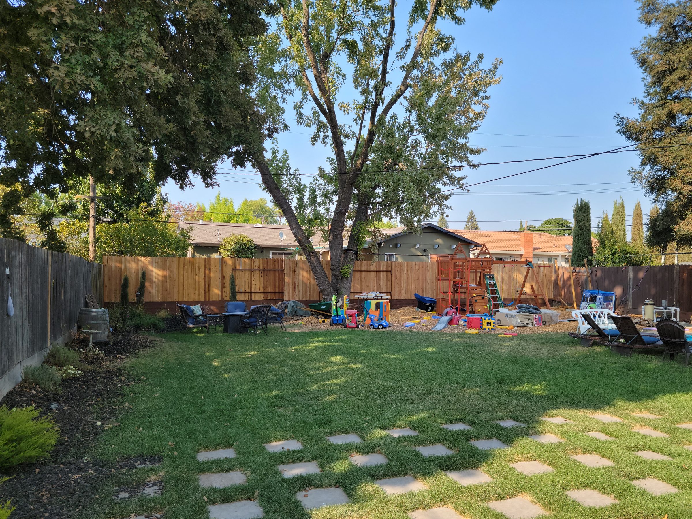 Backyard with a new wood fence along the back and a lawn with stepping stones