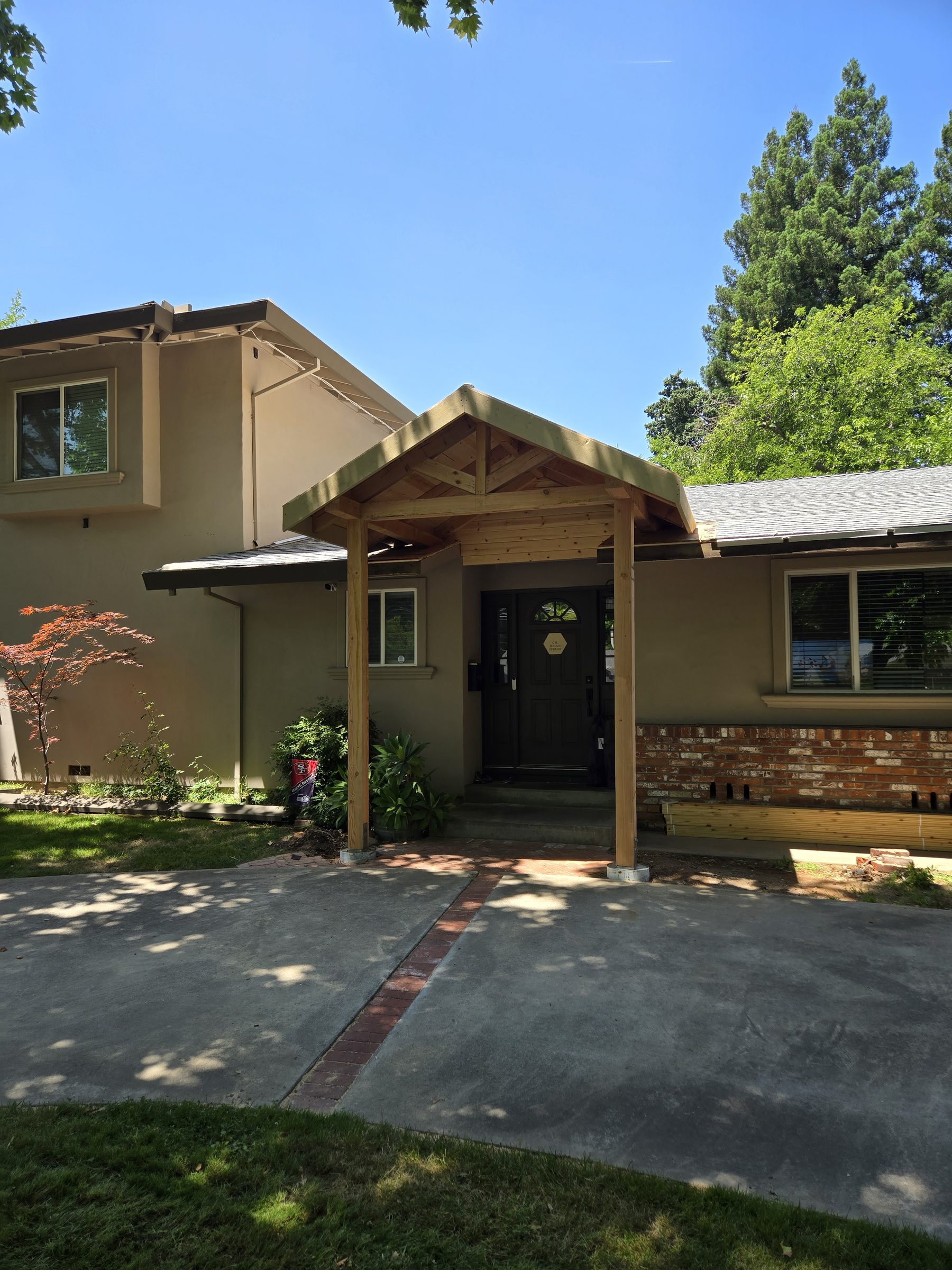New gabled wood entry porch on the front of a single-story home
