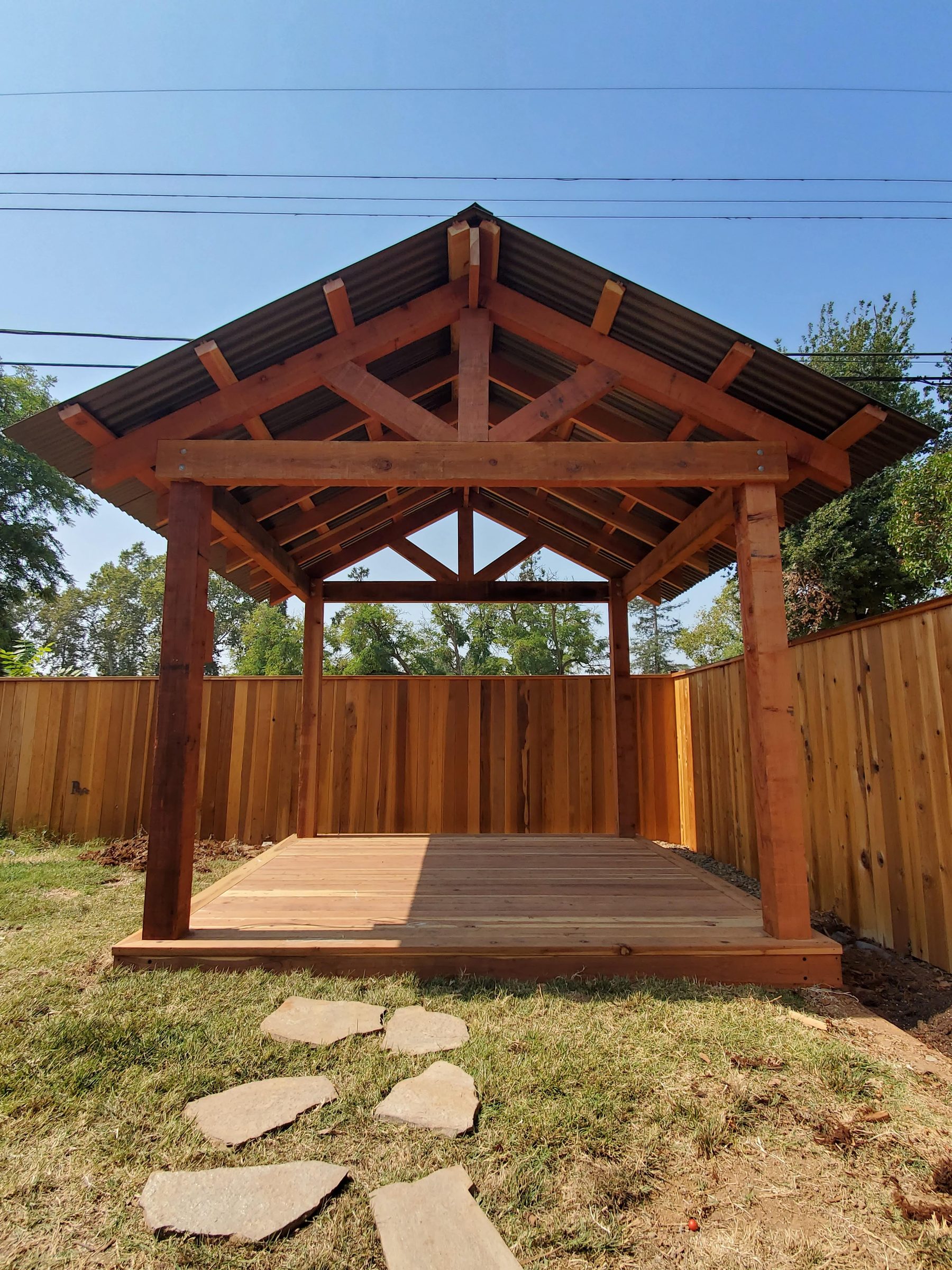 Front view of a timber-framed gable gazebo with exposed rafters and a paver stepping-stone path