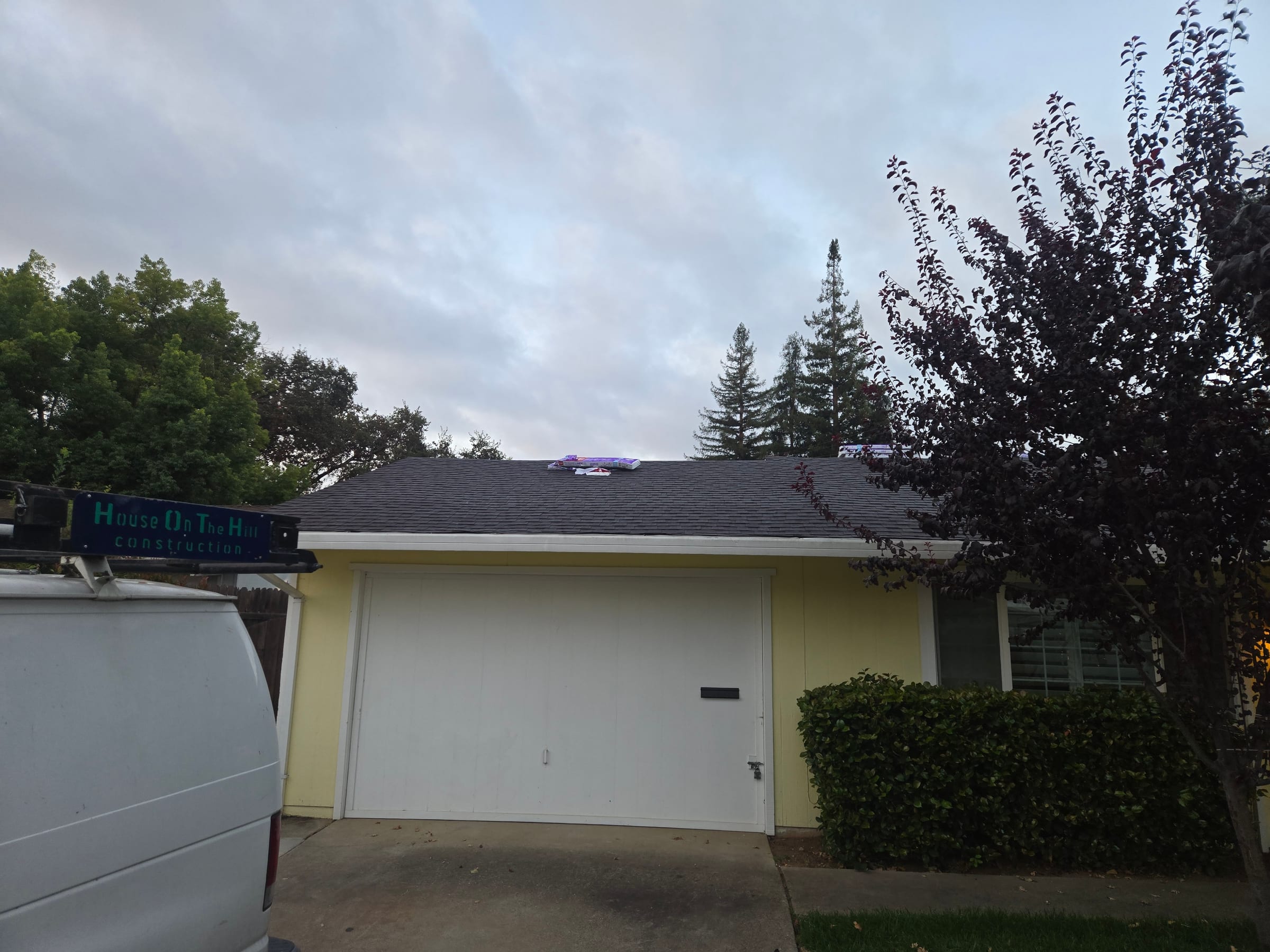 Finished composition shingle roof over the garage with a House on the Hill Construction van parked in the driveway