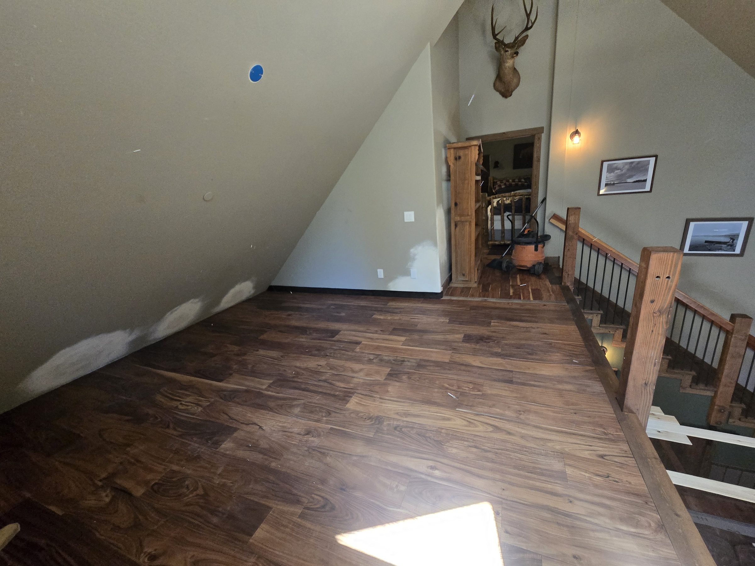 Loft with dark iron railing, cedar ceiling and skylights above a living area