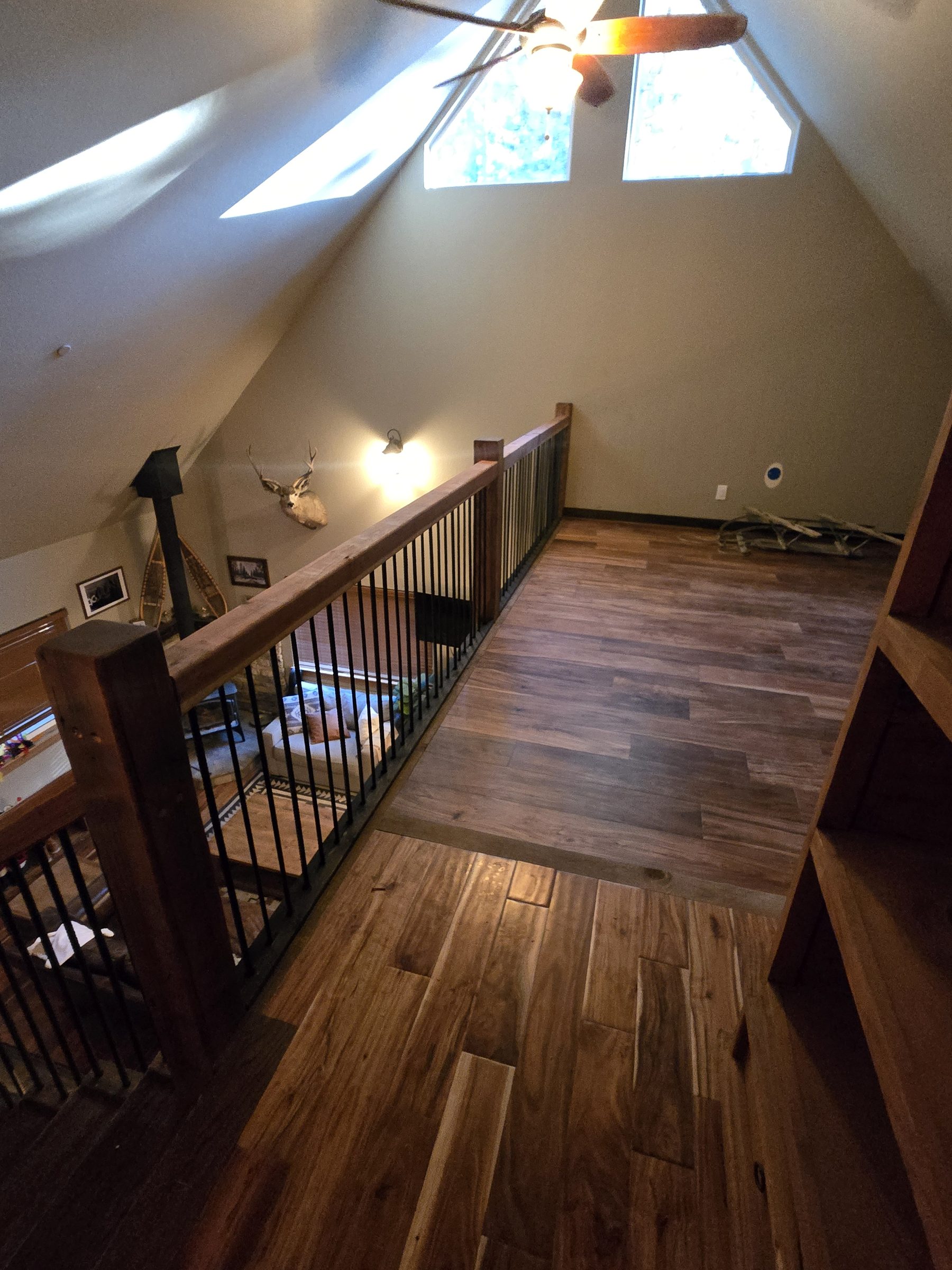 Loft landing with hardwood floors, stair railing and ceiling fan