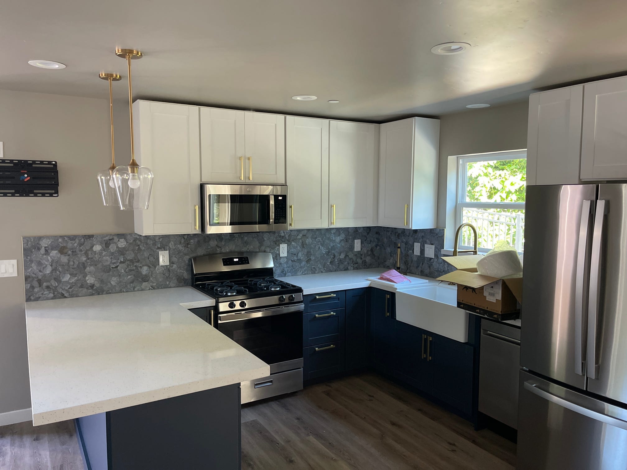 Navy and white kitchen with brass hardware and a gray mosaic tile backsplash