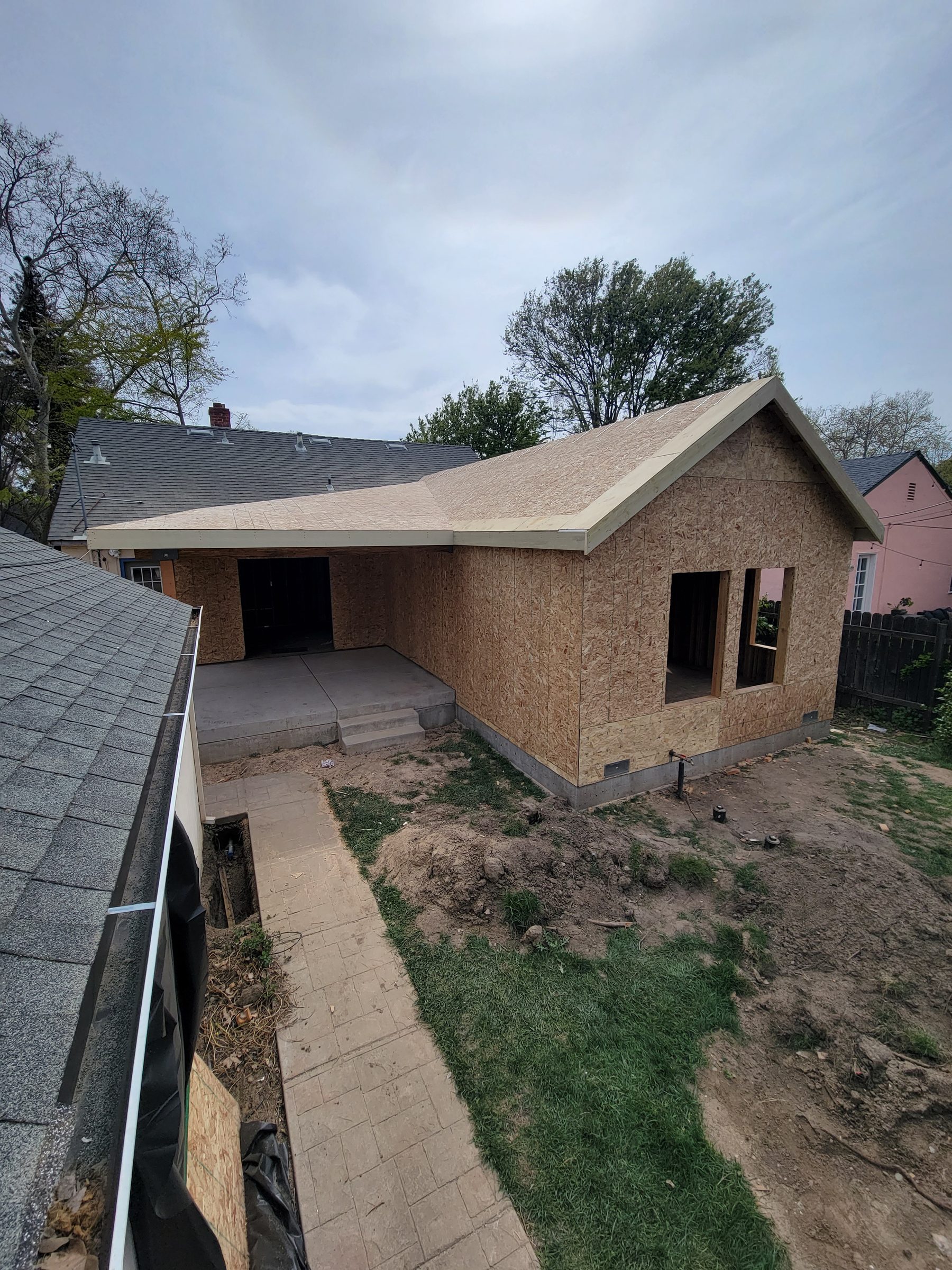 Rear view of a new addition with plywood-sheathed walls and roof