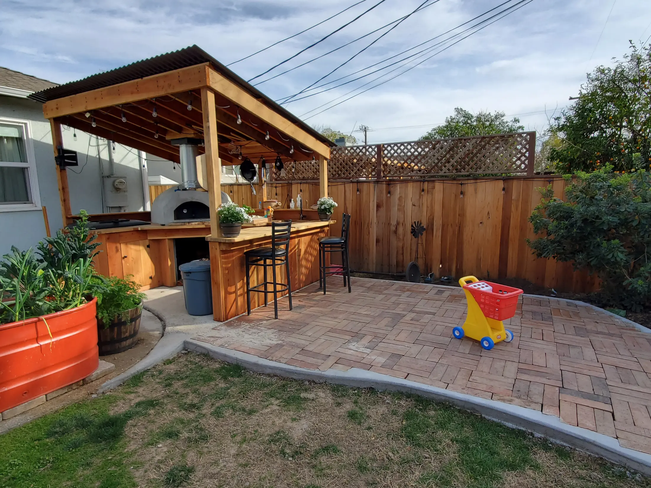 Finished backyard pizza oven kitchen with wood counters and covered seating