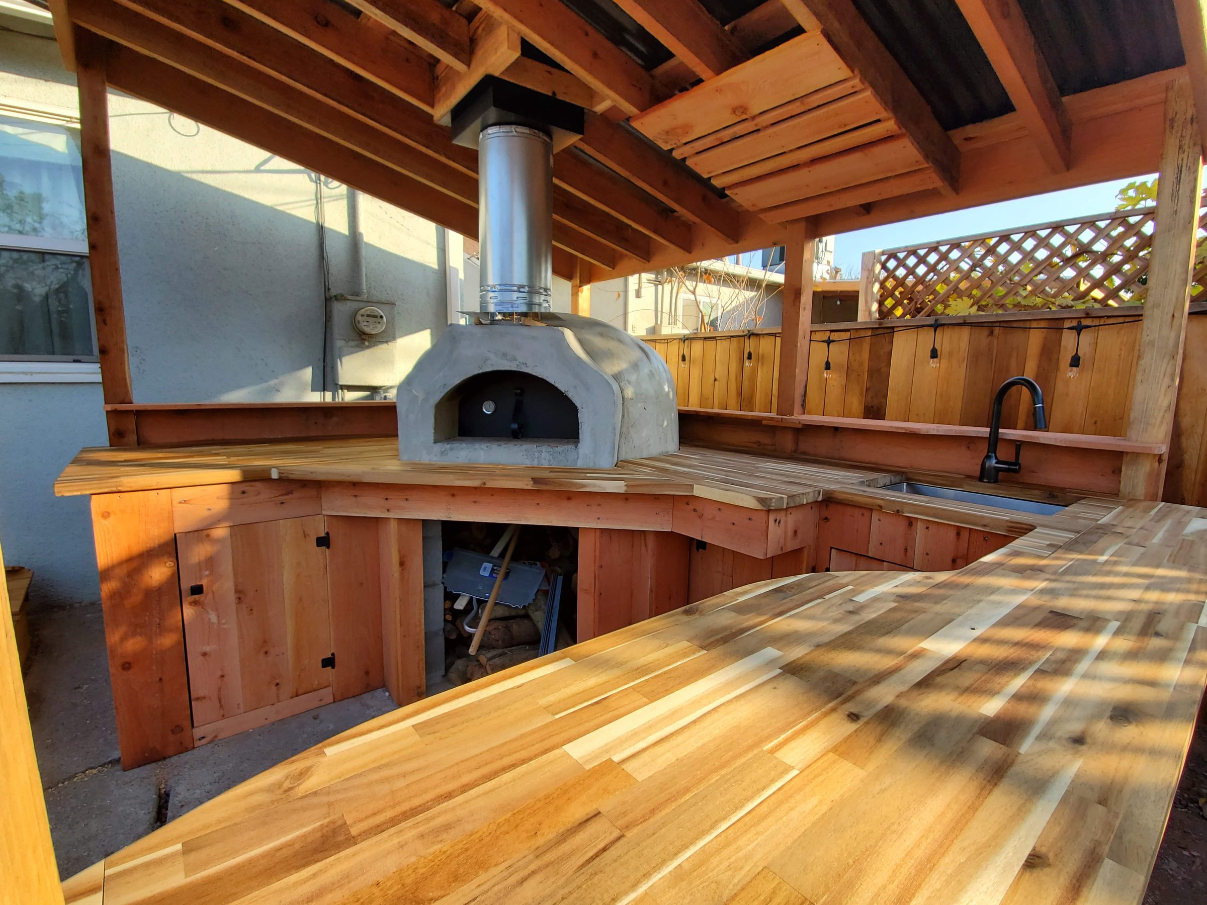 Outdoor kitchen with a built-in pizza oven, wood counters, and a covered roof