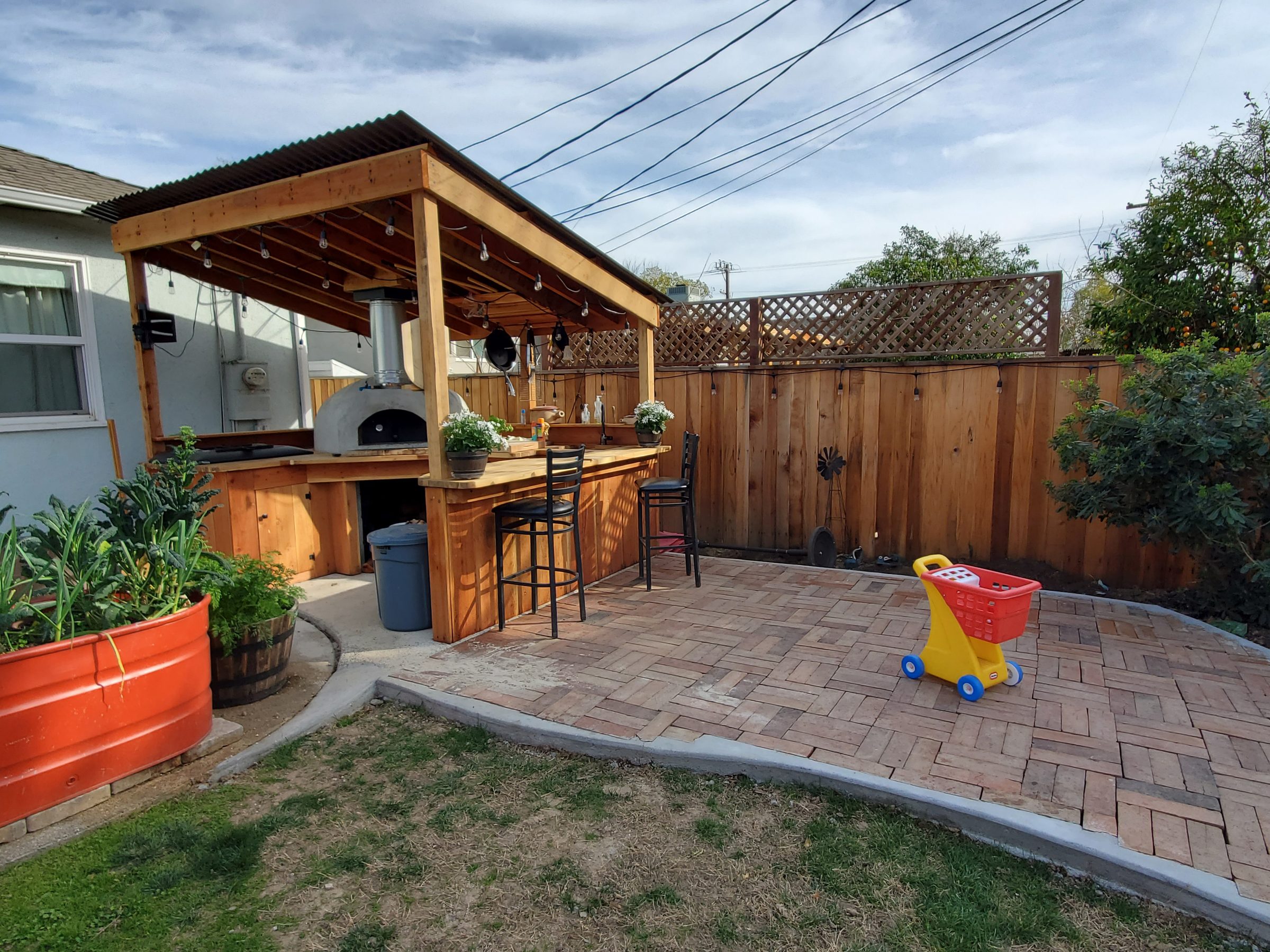 Covered outdoor kitchen and bar seating on a brick patio