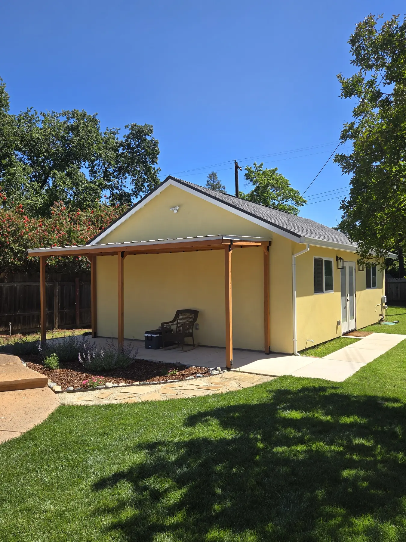 Completed poolside shade structure viewed across a landscaped lawn