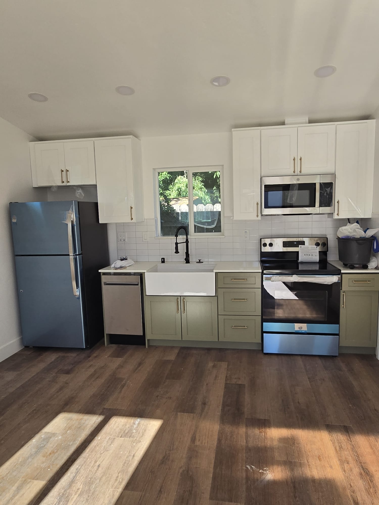 Kitchen with sage green lower cabinets, white upper cabinets, and a farmhouse sink